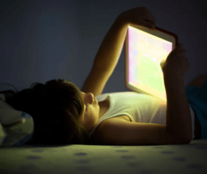young kid in bed reading from a tablet
